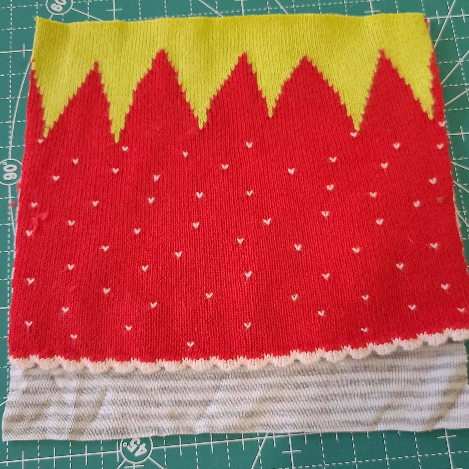 Auf einem neutralen grau-weiß gestreiften Quadrat liegt die aufgeschnittene Erdbeermütze so, dass etwa 3 cm des neutralen Quadrates unten herausschauen.